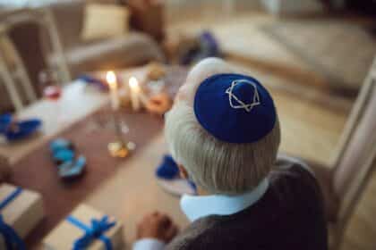 Close up of senior Jew lighting the menorah on Hanukkah.